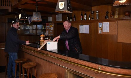 Zwei Männer stehen in hinter einer leeren Bar und öffnen einen Karton