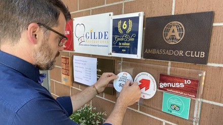 Inhaber Martin Ettisberger vom Hertenstein Panorama-Restaurant in Ennetbaden beim Anbringen der Auszeichnungsplakette an der Wand.