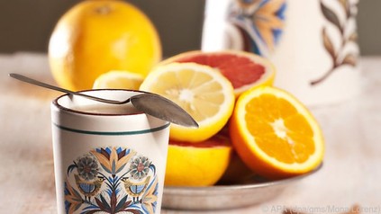 Tasse mit Löffel und Orangenschale im Hintergrund
