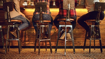 Vier Männer sitzen an einer Bartheke