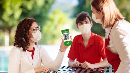 Frau zeigt im Restaurant den Impfnachweis