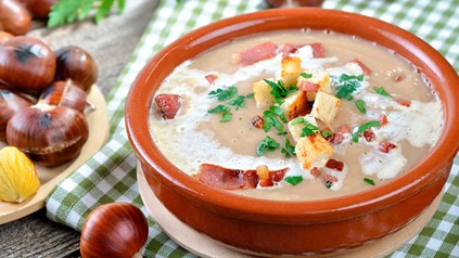 Maronencremesuppe in einer Schüssel, daneben liegen frische Maronen