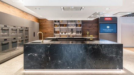 Hochwertige natürliche Materialien wie Glas, Holz und Stein prägen das moderne und warme Ambiente. Der offene Küchenbereich wirkt einladend und transparent.