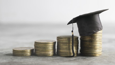 kleine Münzstapel mit einem Doktor-Hut