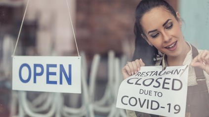 Gastronomin nimmt Closed-Schild ab und hängt OPEN an die Tür