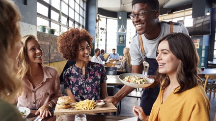 Servicekraft bringt Essen an den Tisch