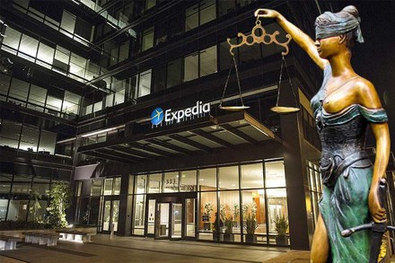 Das Bürogebäude von Expedia von außen und eine Justitia Statue daneben