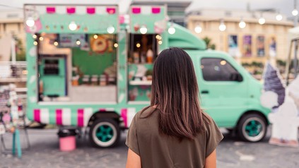 Junge Frau geht auf einen Food Truck zu
