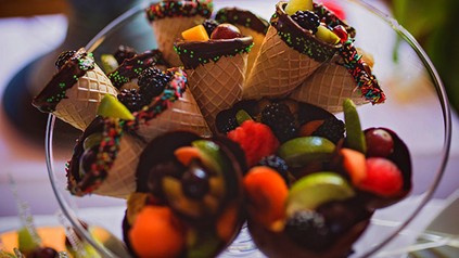Mehrere Eiswaffeln mit Schokolade und Früchten in einer Schüssel