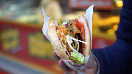 Eine Person hält einen frischen Döner in der Hand