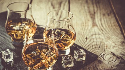Drei Whiskygläser mit Eiswürfeln und Whisky