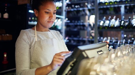 Junge Frau tippt etwas in eine elektronische Registrierkasse ein