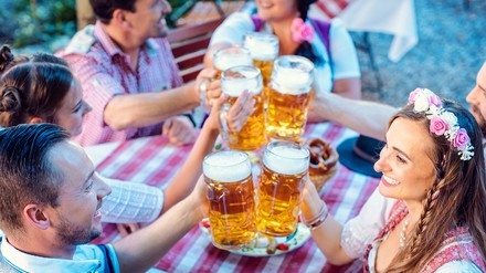 Freunde stoßen im Biergarten mit den Krügen an