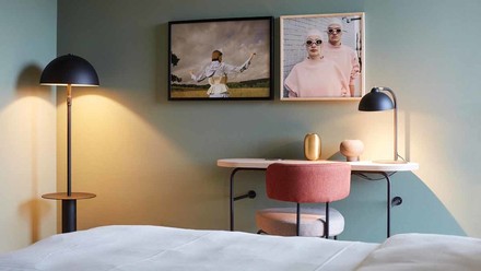 Blick vom Bett auf den Schreibtisch in einem minimalistisch stylischen Hotelzimmer in Pastelltönen