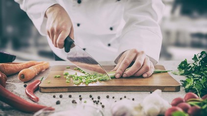 Koch schneidet Lauch auf dem Küchenbrett