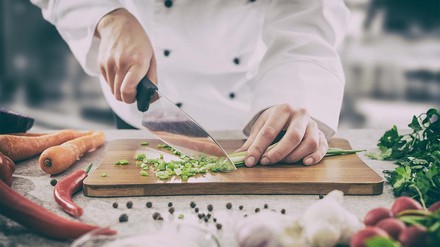Koch schneidet Lauch auf dem Küchenbrett