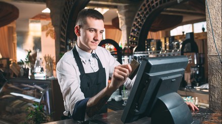 Gastronom gibt etwas in die elektronische Kasse ein