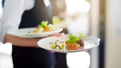 Eine Servicekraft serviert zwei Gerichte