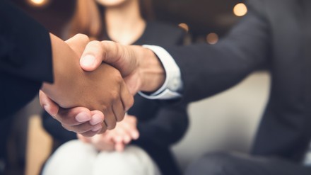 Zwei Menschen im Anzug geben sich die Hand