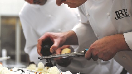 Nahaufnahme eines Kochs mit einer Kochjacke, auf der das JRE-Logo der Jeunes Restauranteurs, der Vereinigung junger Spitzenköche, zu sehen ist