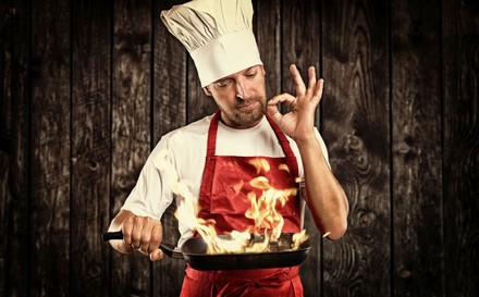 Koch hält brennende Pfanne