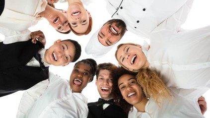 Köche und Servicekräfte halten sich lachend gegenseitig im Arm