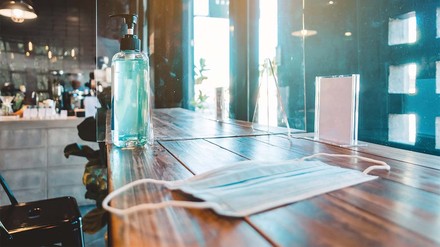 MAske und Desinfektionsmittel auf Restauranttisch