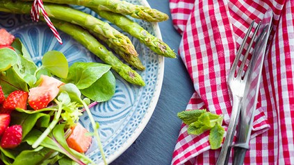 Ein Teller mit Spargel und frischem Salat mit Kräutern