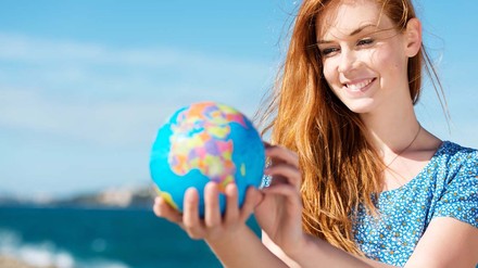 Junge Frau studiert die Weltkugel in ihrer Hand