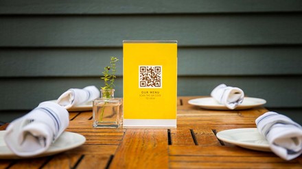 Aufsteller mit QR-Code für die Speisekarte auf dem gedeckten Tisch
