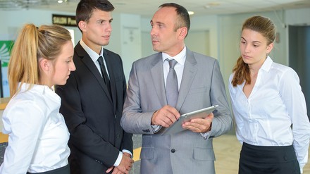 Ausbilder im Hotel zeigt seinen Auszubildenden etwas auf dem Tablet