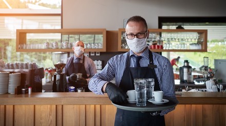 Ein Kellner mit Mundschutzmaske