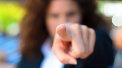 Eine Frau zeigt anklagend mit dem Finger auf jemanden