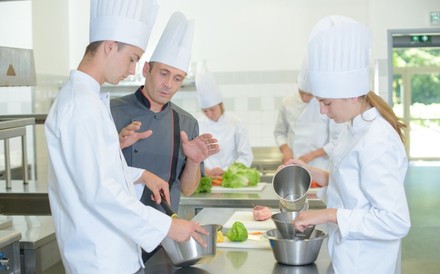 Koch gibt Auszubildenden in einer Küche Tipps