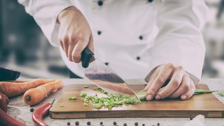 Koch schneidet Lauchzwiebeln in feine Scheiben