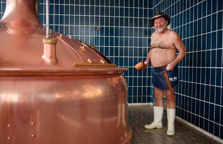 Jürgen Hopf nur mit Gummistiefeln, Hut und Lendenschurz bekleidet beim Bierbrauen