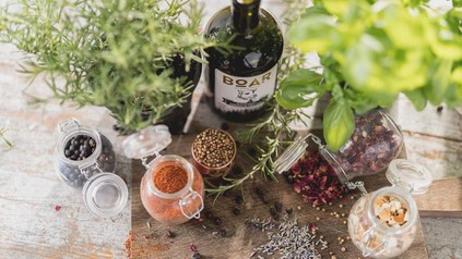 Eine Flasche Boar Gin steht inmitten der Zutaten für die Zubereitung