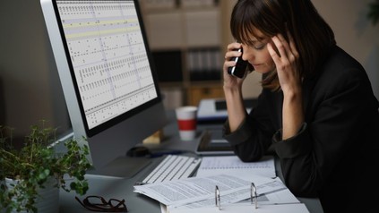 Frau telefoniert und hat Arbeitsunterlagen auf dem Tisch
