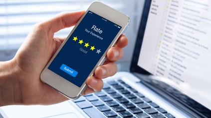 Person bewertet sein Erlebnis mit vier Sternen auf dem Smartphone