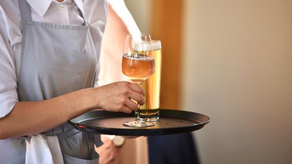 Ein Zimmermädchen mit einem Bier in der Hand