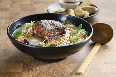 Eine Schüssel Ramen auf einem Holztisch mit einem Holzlöffel