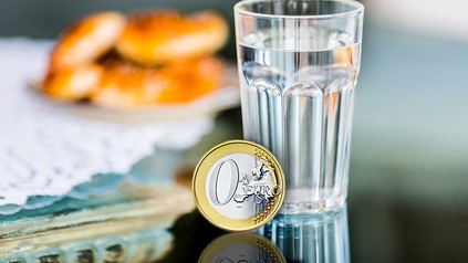 Ein Glas Wasser und ein Null-Euro-Stück daneben