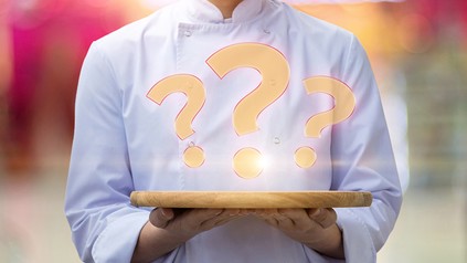 Ein Koch serviert ein Fragezeichen auf einem Tablett