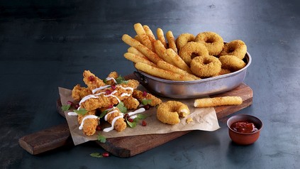Homestyle Chik’n® Fingers Buttermilk, vegetarische Mozzarella Fries und Mozzarella Onion Rings angerichtet in einer Metallschale auf einem Holzbrett
