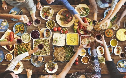 Gruppe sitzt gemeinsam an Esstisch und speist