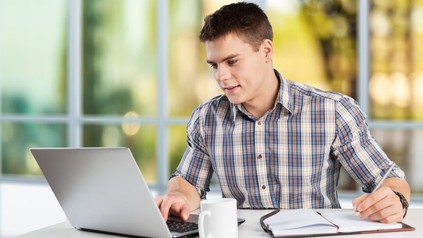 Mann arbeitet an Laptop mit Kaffee