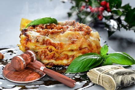 Dampfende Lasagne neben einem Richterhammer und einem Stapel Geldscheine
