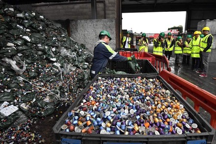 Eine Gruppe Personen auf einer Mülldeponie auf der besonder die Kaffeekapseln gelagert werden