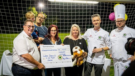 Köche mit einem Spenden-Scheck