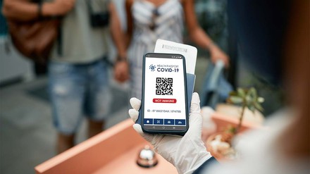 Rezeptionistin überprüft am Handy den Impfnachweis eines Gastes